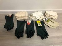 Lot of 12 pairs of work gloves including three types: green waterproof puncture-resistant Edmont Snorkel gloves, light fabric gloves, and off-white thick fabric gloves.