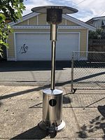 Full view of the stainless steel patio heater showing its tall structure, cylindrical base, and wide reflective top.