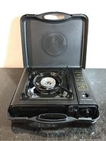 Front view of black National Tiger portable gas stove with single burner, lid open showing burner and control knob.