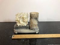 Front view of the stone brush stand showing the cylindrical holder and sculpted tree/coral piece on the layered base with a ruler for scale.