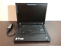 Open Lenovo ThinkPad laptop with keyboard and charger plugged in.