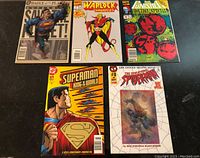 Top-down view of five vintage comic books and one Superman figurine arranged on a dark surface