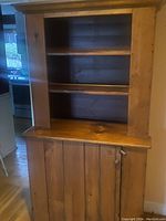 Front view of pine wood cabinet showing three open shelves above and a closed door with knob below.