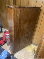 Side view of tall wooden bookshelf showing wood grain and wear on finish.