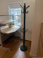 Full view of the assembled green wicker coat stand standing in a corner by a window.