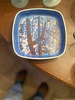 Top view of square Aluminia fajance dish showing blue and brown intricate floral and geometric design with white rim.