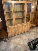 Full view of the midcentury wood china cabinet with closed glass doors, showing the cabinet's shape and finish.
