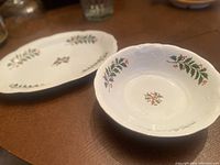 Photo showing oval platter and round bowl on table with Christmas holly pattern.
