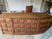 Front view of wood credenza showing the carved geometric panel sliding doors