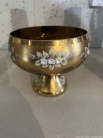 Full view of antique gold painted glass vase with floral trim on pedestal base.