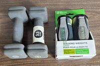 Two pairs of exercise weights; gray 4 lb walking weights with straps on original packaging and two gray 5 lb neoprene hand weights.