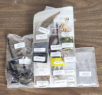 Various labeled fly tying materials including pheasant tail, dubbing types (Adams, Hare's Mask), marabou, deer body hair, peacock herl, mallard flank, cream feathers, and duck quills arranged on a wooden surface.