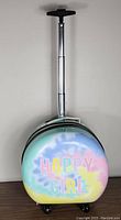 Full view of round rolling hard case bag with fully extended handle showing tie-dye pattern and text 'HAPPY GIRL'.