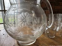 Close-up of large glass pitcher showing detailed etched cornflower floral pattern.
