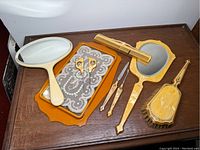 Top view of the full dresser set on a wooden surface showing all included items: tray, hand mirror, smaller mirror, comb, scissors, and two manicure tools.