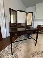Full view of dark wood Empire style vanity table with tri-fold mirror and three drawers.