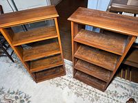 Pair of wooden book shelves showing front and top views, displaying four shelves each with visible wood grain and some surface wear.