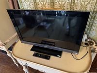 Sony Bravia 32 inch television front view showing screen, bezel, and remote on surface.