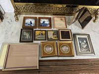 Image showing all framed items arranged on the floor including various prints, two gold round frames, and a silver frame with cat picture.