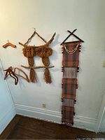 Photo showing the full grouping of vintage wall hangings on wall, including macramé pieces, woven textile piece, and wooden hangers