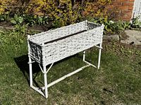 Full view of white wicker plant stand with tin liner outdoors on grass showing the overall structure and height.