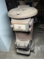 Front view of Classic Jewel wood burning stove showing front door with handle and vent, dusty and rusty surface.