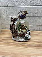 Front and side views of the Lenox snow globe with Santa in sleigh, reindeer pulling, snowman and Christmas cabin inside the globe