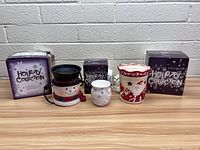 Lot of 3 Scentsy warmers with original boxes on a white surface against a grey brick wall