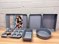 Six Pioneer Woman baking pan pieces arranged on a table showing different shapes and embossed floral patterns.