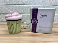 Cupcake-shaped ceramic Scentsy wax warmer next to original box, showing front and side view of item with electric plug cord