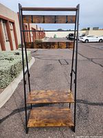 Front view of shelf with hooks showing three wooden shelves on metal frame