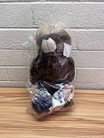 Front view of Smokey the Bear plush sealed in plastic packaging, showing clear details of bear face and fabric items held