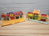 Side view of yellow base playset with Shopping Mall, Garage, and Bank buildings labeled with colorful signs and architectural details.