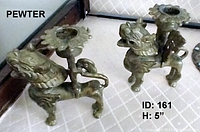 Pair of pewter or metal dragon candle holders with intricate details, standing side by side on a patterned surface.