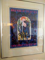 Framed colorful lithograph with an arched centerpiece showing stylized nature elements and surrounding script text.