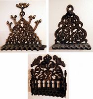Three different cast metal hanging hooks with ornate detailed tops and multiple hooks at the base, shown mounted on a wall.