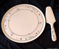 Full view of the round serving platter and matching server with white background and floral pattern.