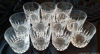 Set of 11 old-fashioned clear glass drinking glasses arranged together showing the patterned cut glass design and size.