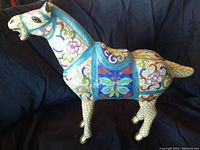 Side view of cloisonné horse showing colorful enamel floral and butterfly inlay