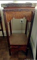 Side view of one wooden side table with carved detailing showing square top and supportive base.