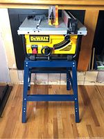 Front view of saw on stand showing DeWalt logo, adjustment knobs and stand