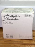 Front of white box labeled “American Standard Complete Toilet”