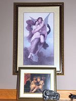 Photo showing the large framed angel print mounted on wall with the two smaller items placed below on a shelf: smaller framed angel print and angel plaque.