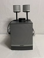 Front view of the subwoofer with two satellite speakers and the remote control unit on top.