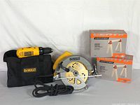 DeWalt cordless drill, soft black carrying case, DeWalt circular saw, and two unopened boxes of Certified sawhorse brackets grouped on white background.