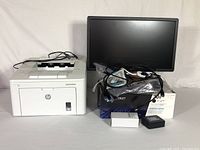 Lot overview including HP LaserJet Pro printer, Dell 21-inch monitor, toner cartridges, cords and accessories