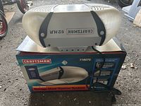 Main opener unit with power cord placed on its box, showing Craftsman branding and 1/2 HP label.