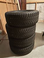 Stack of four tires mounted on rims shown from an angle