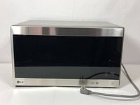 Front view of LG stainless steel microwave oven with black glass door and digital control panel