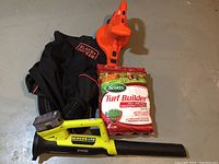 Photo showing Black & Decker 3-in-1 Vacpack, Ryobi cordless leaf blower with battery installed, and one unopened bag of Scotts Turf Builder.